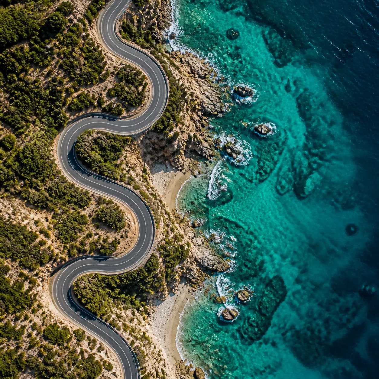 Aerial photography example looking down at a coastal road and turquoise shoreline.